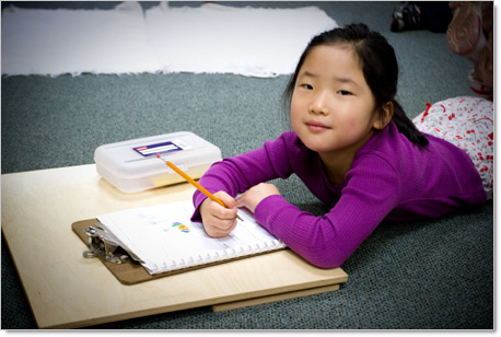 smiling montessori kindergartner drawing during class