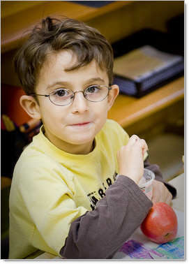 prek boy in classroom wearing yellow shirt wearing glasses