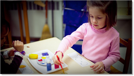 young girl painting during montessori play school